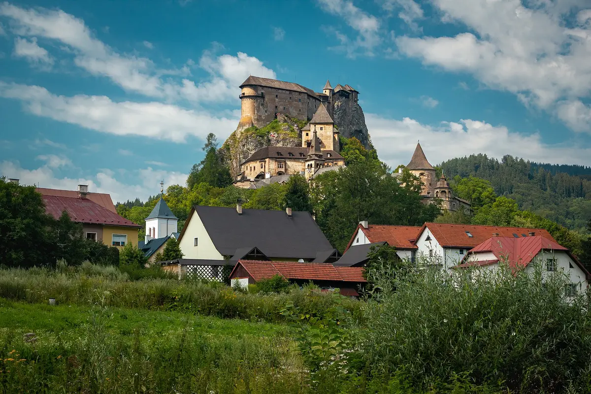 Orava Castle on its rock above the houses and church of Oravský Podzámok, with wooded hills behind